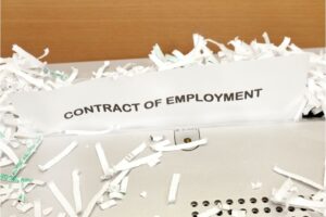 Image of a piece of paper that says "contract of employment" in a paper shredder